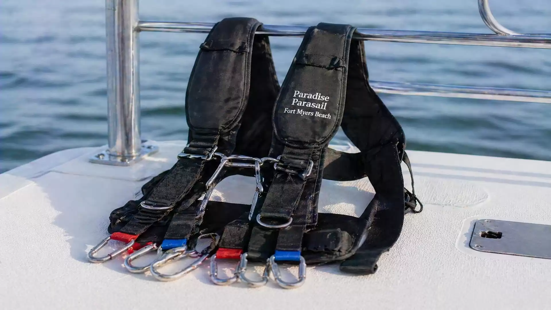 Two black parasailing harnesses on a boat with the sea in the background.