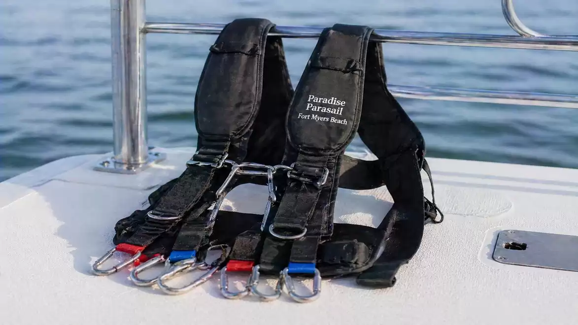 Two black parasailing harnesses on a boat with the sea in the background.