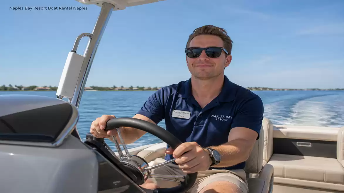 A man is steering a boat on calm water under sunny weather. He is wearing sunglasses and a dark blue polo shirt.