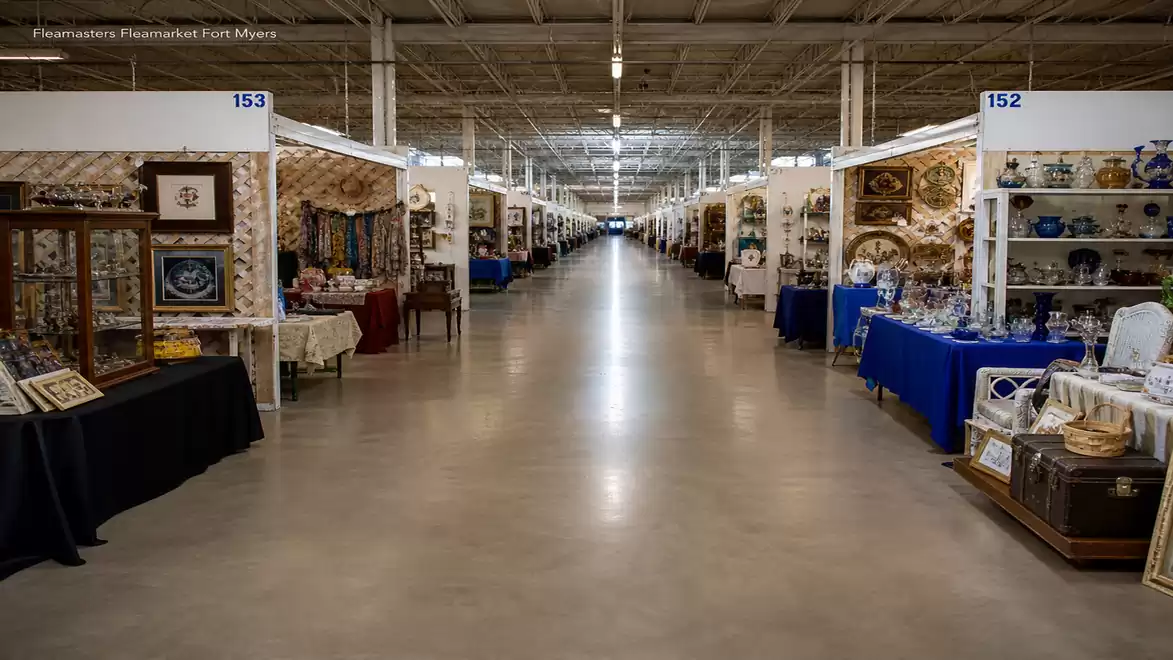 A large antique center featuring numerous booths displaying antiques and artworks. The aisles are long and well-lit, with many interesting exhibits on both sides.