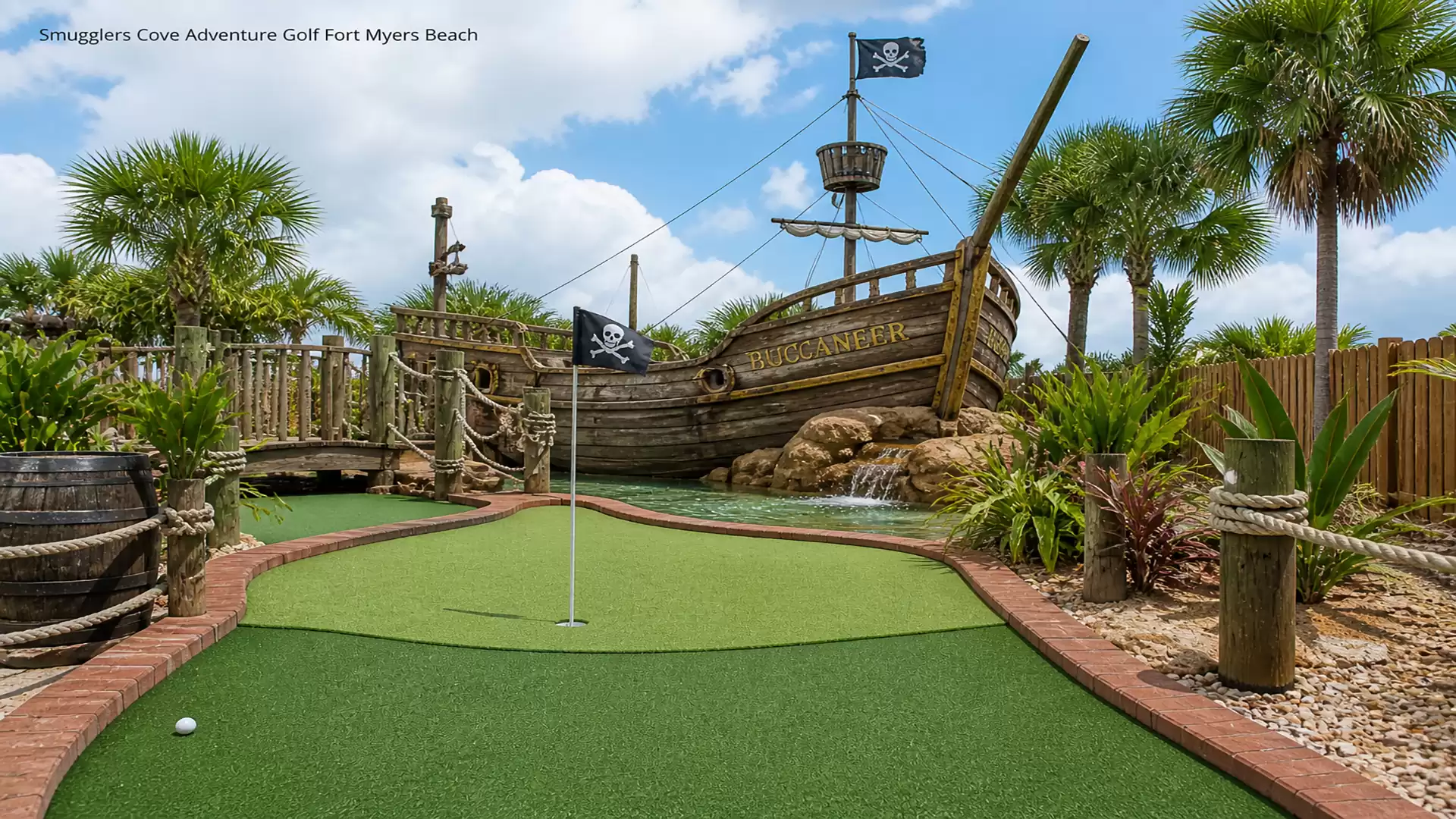 An adventure golf course in Fort Myers Beach featuring a pirate ship, green lawn, and palm trees under a blue sky.