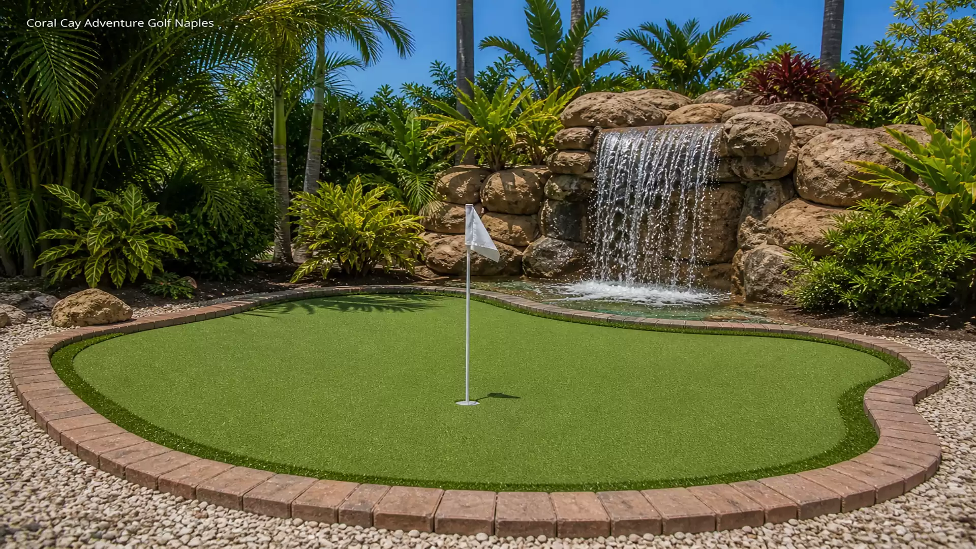 Miniature golf course with a small waterfall and lush tropical vegetation.