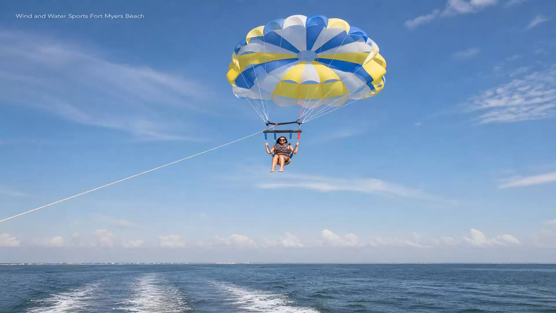 Person parasailing over a clear blue ocean on a sunny day.