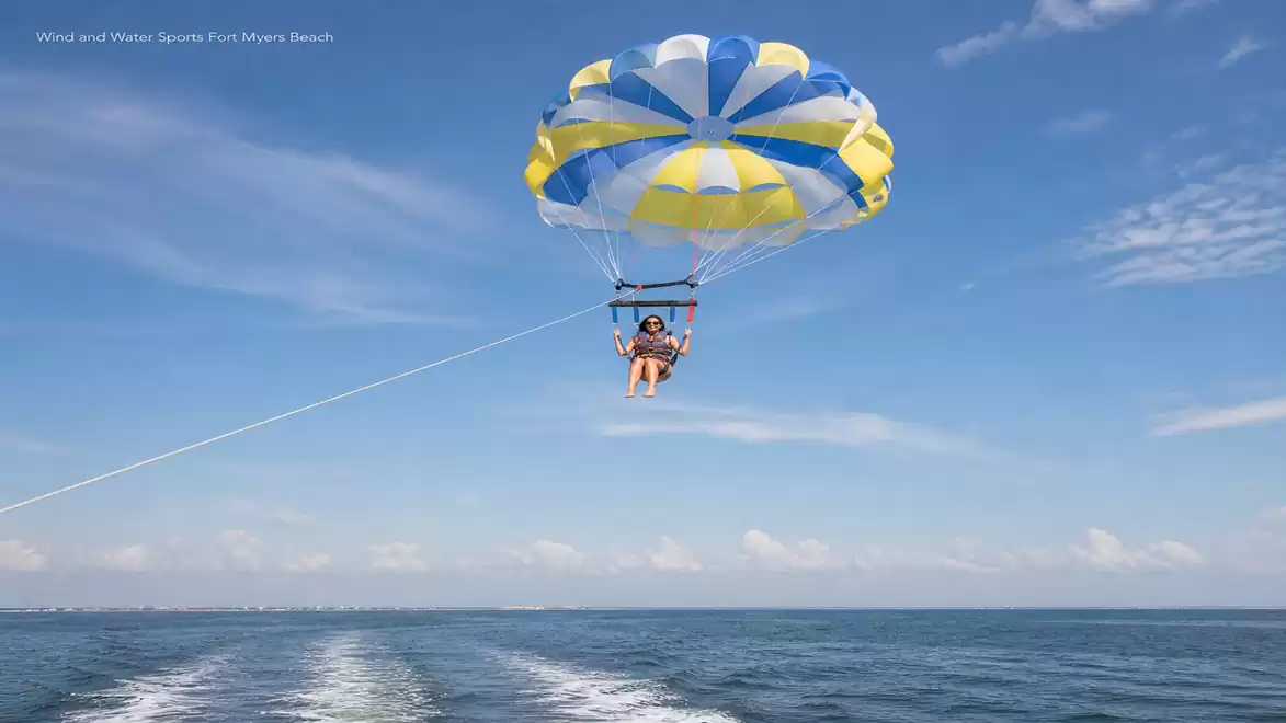 Person parasailing over a clear blue ocean on a sunny day.