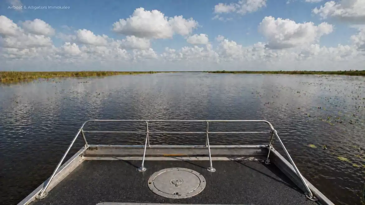 Boat deck overlooking a vast water surface and sky with white clouds.
