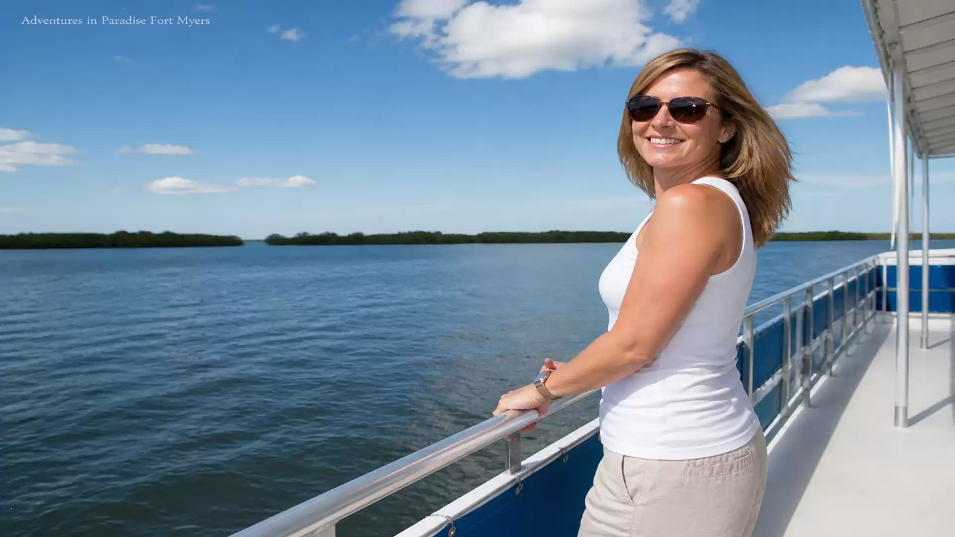 Woman enjoying the view on a boat trip on a calm lake under a blue sky.