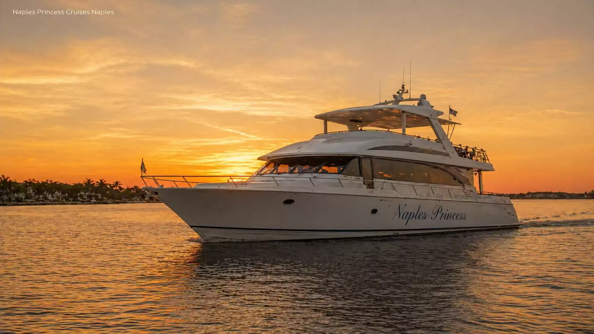 A luxurious yacht sails on calm waters during sunset, with the sky glowing in warm orange hues.