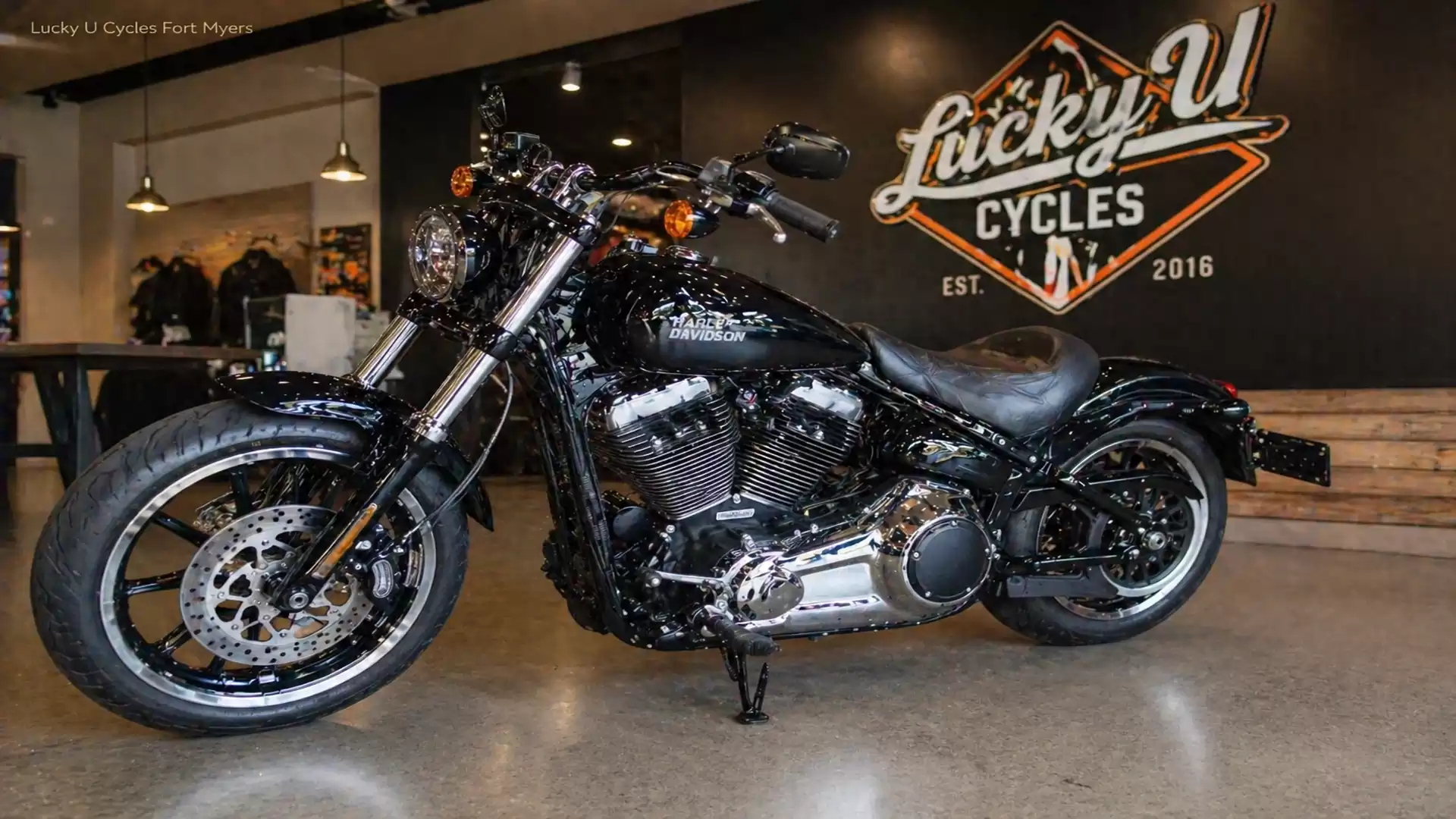 Black motorcycle inside a showroom of Lucky U Cycles, featuring polished metal elements and leather details.