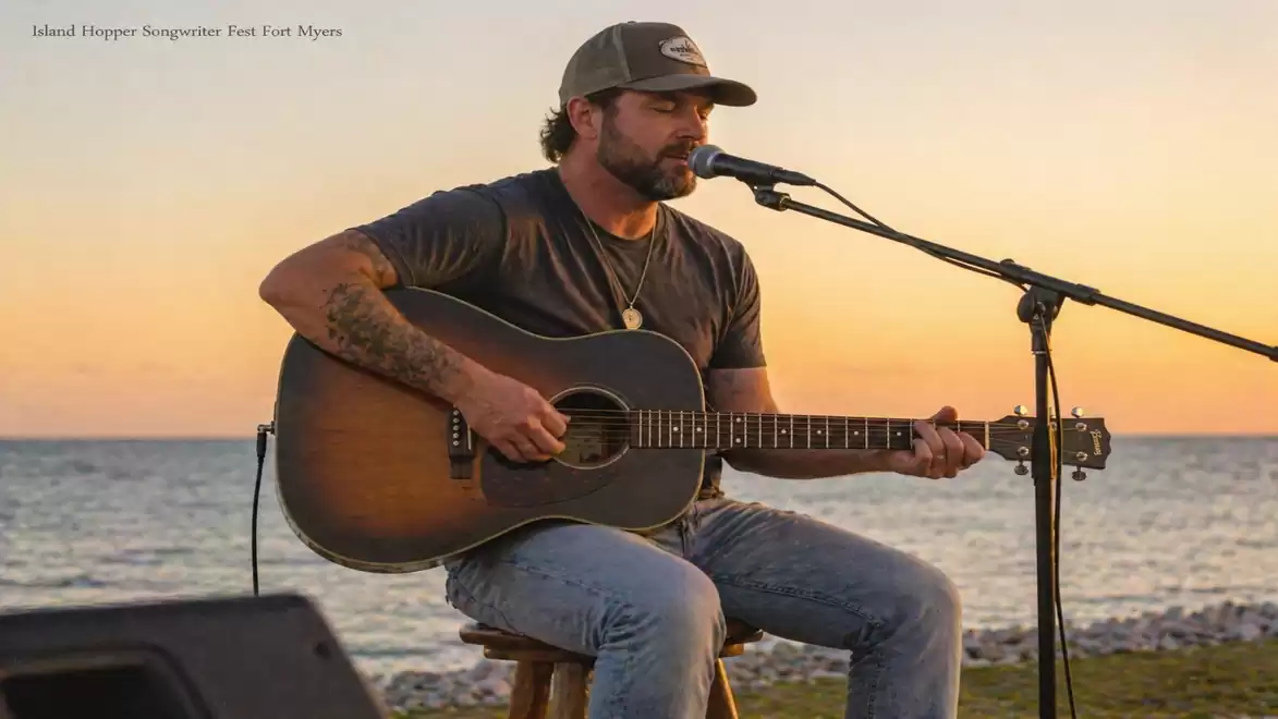 A musician playing guitar and singing by the sea during sunset.