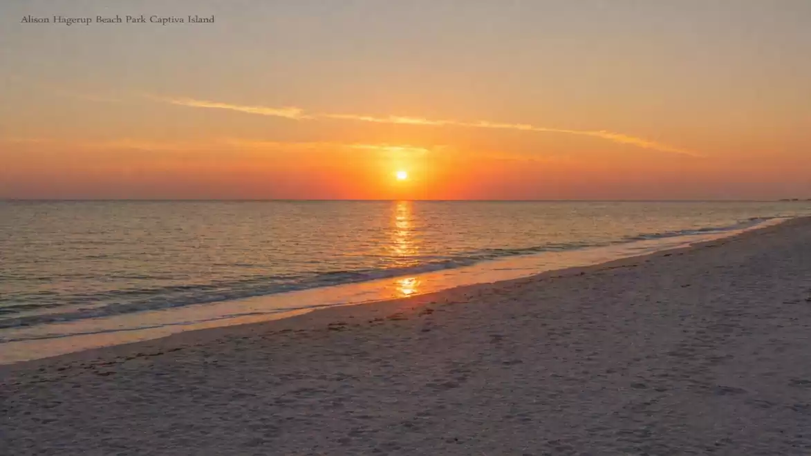 Sunset at a calm beach with gentle waves and orange sky.