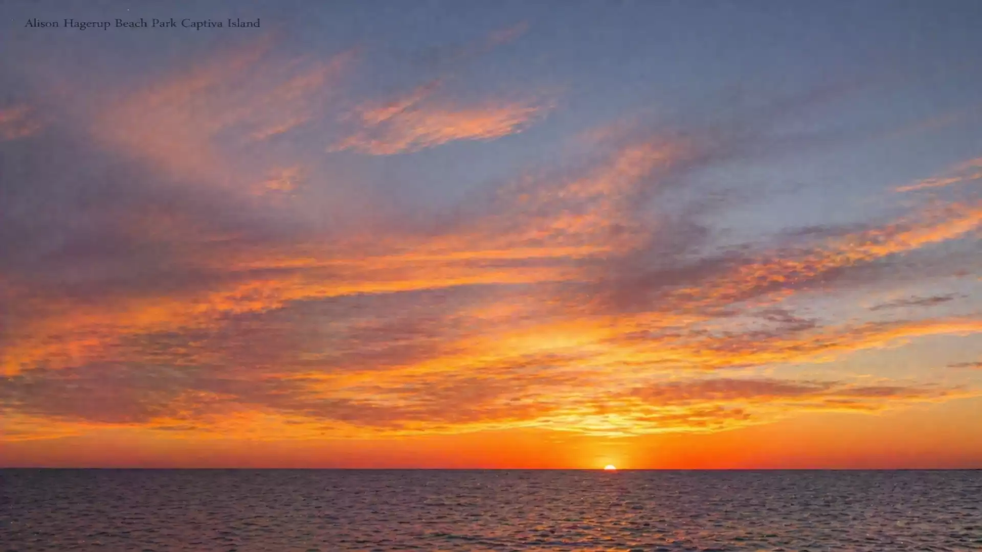 A breathtaking sunset over the sea with a sky full of vibrant orange and blue hues.