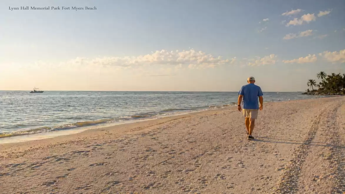 A man walks along the beach at sunset with a calm sea background.