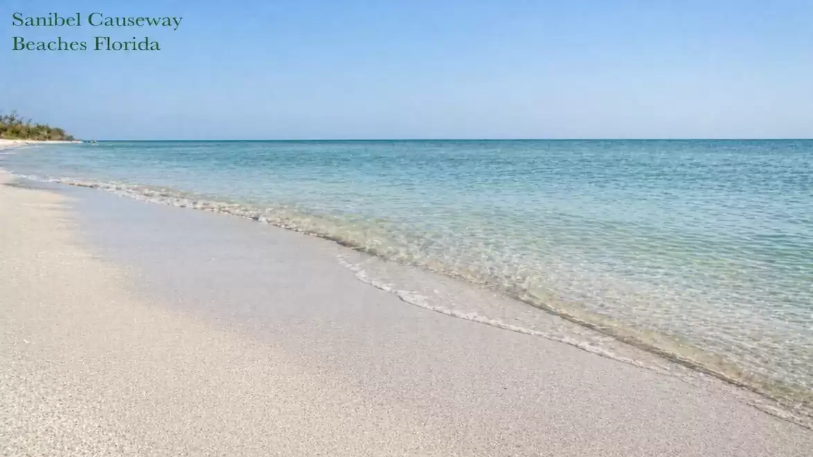 A serene, sunny beach with clear blue water and white sand at Sanibel Causeway in Florida.