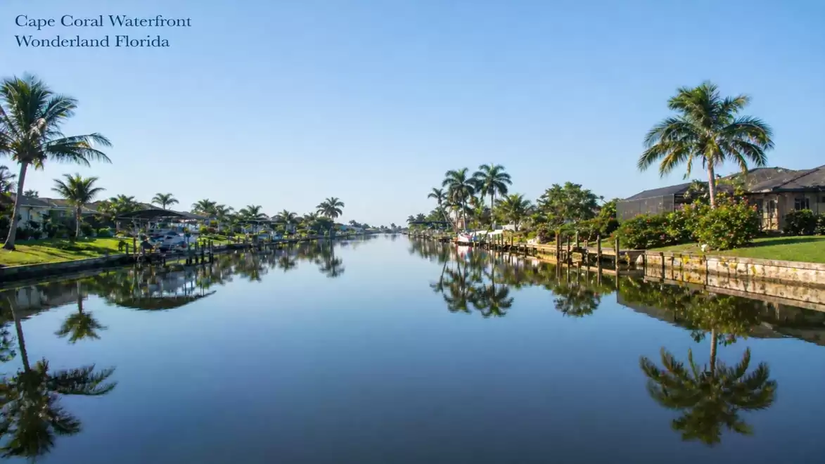 Calm canal in Cape Coral, Florida with palm trees and clear reflection in the water.