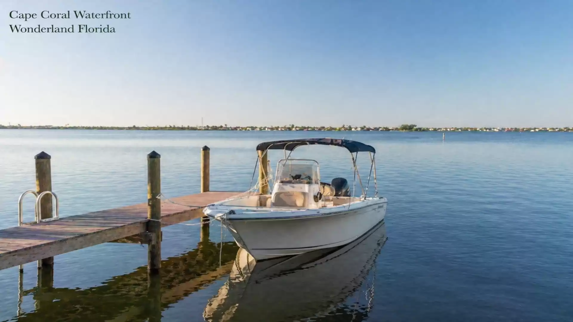 A motorboat docked at a wooden pier on the calm waters of Cape Coral Waterfront in Florida.