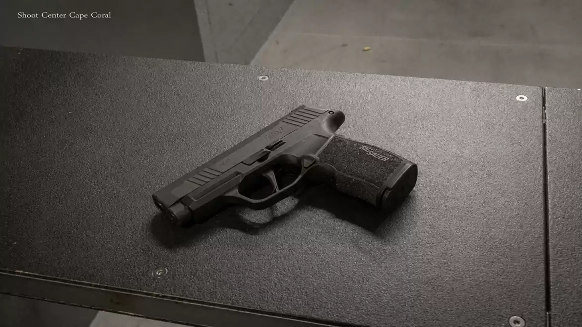 A black handgun is lying on a gray table.