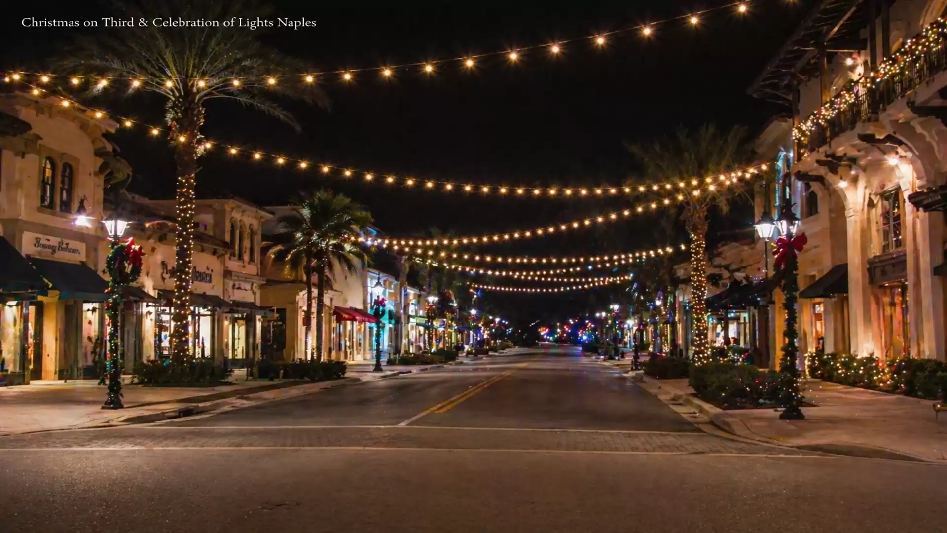 Festively decorated street in Naples with string lights and illuminated palm trees at night.