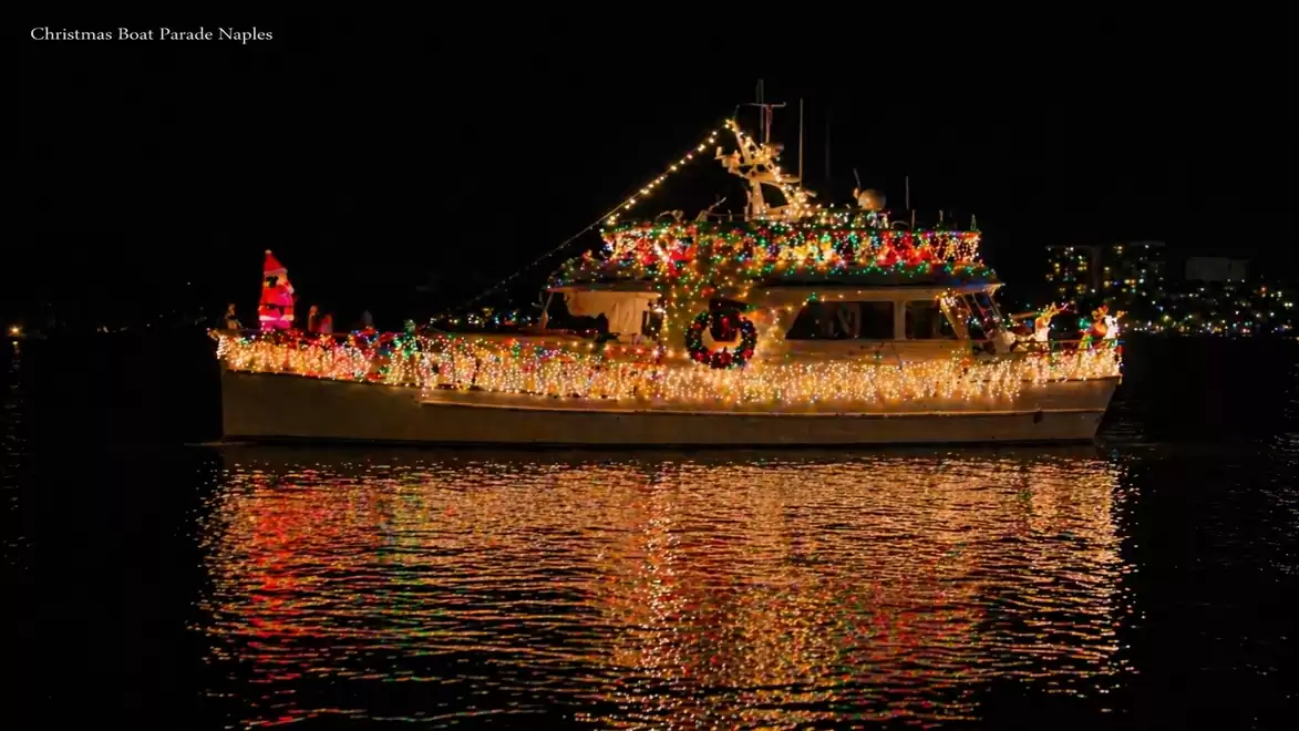 A festively lit boat on dark water at night, adorned with colorful Christmas lights.