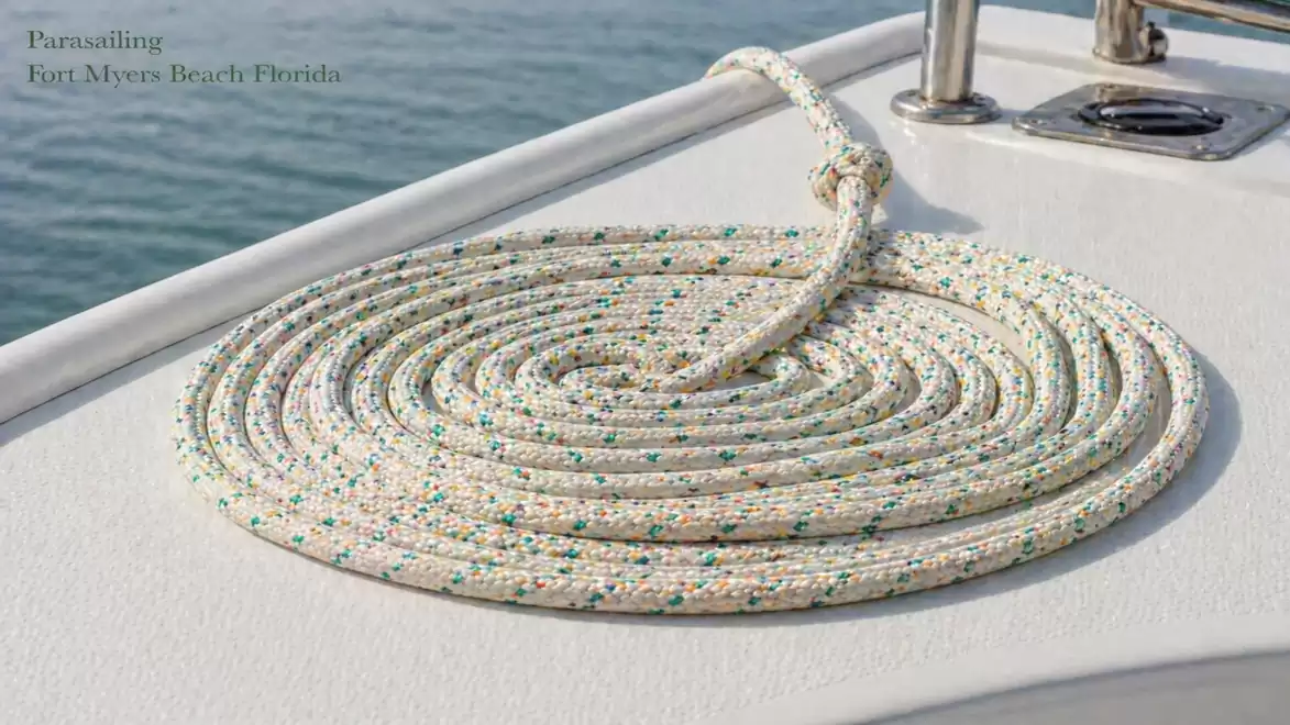 Close-up of a coiled rope on a boat deck. The sea is visible in the background, and the rope has colorful speckles.