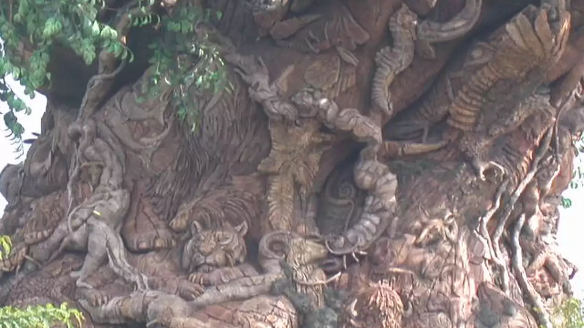 A tree with intricate animal and plant carvings, including a tiger and other animals, sculpted into the wood.