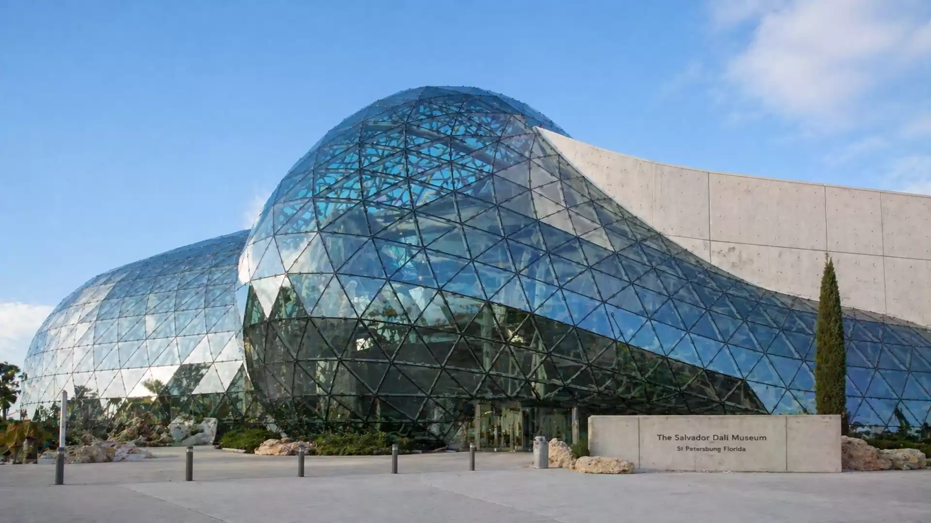Modern glass architecture of the Salvador Dali Museum in sunny weather, featuring futuristic design and blue glass facade.