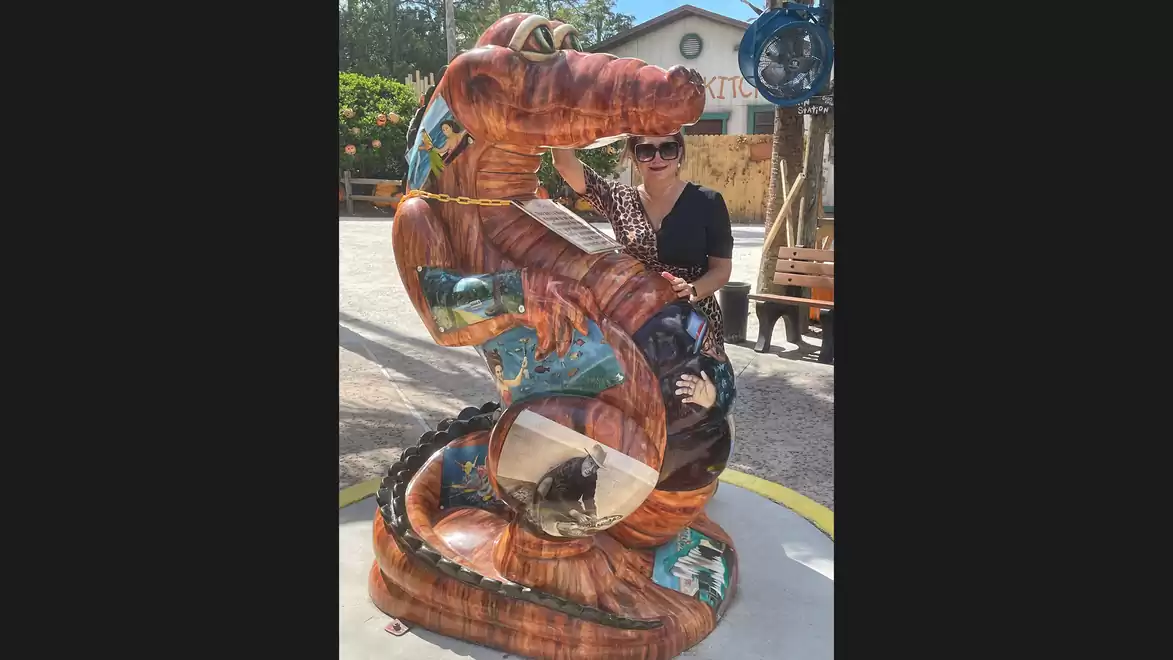 A wooden dragon statue in an amusement park with a person behind it.