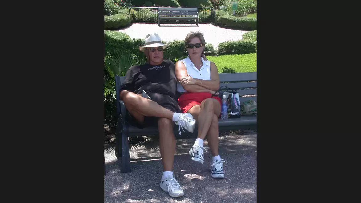 Two people relaxing on a park bench in a sunny garden.