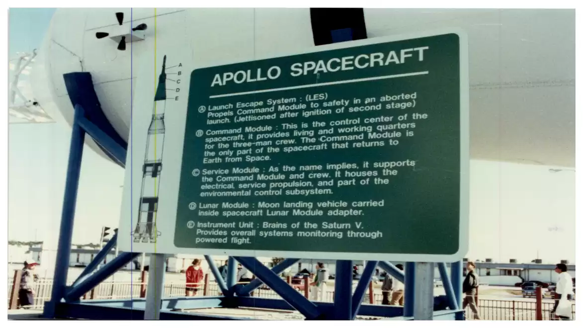 An informational board displaying details about the Apollo spacecraft outdoors, featuring several passages and explanations about various components including the command module and service module.