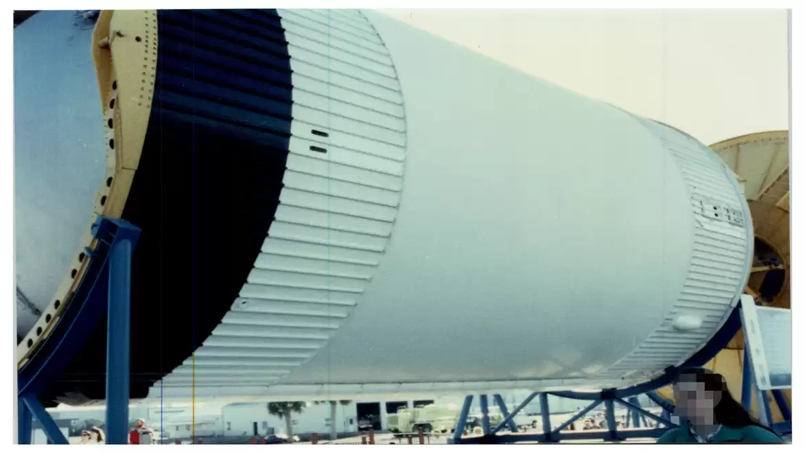 Close-up of a large rocket component stored outdoors on a stand.