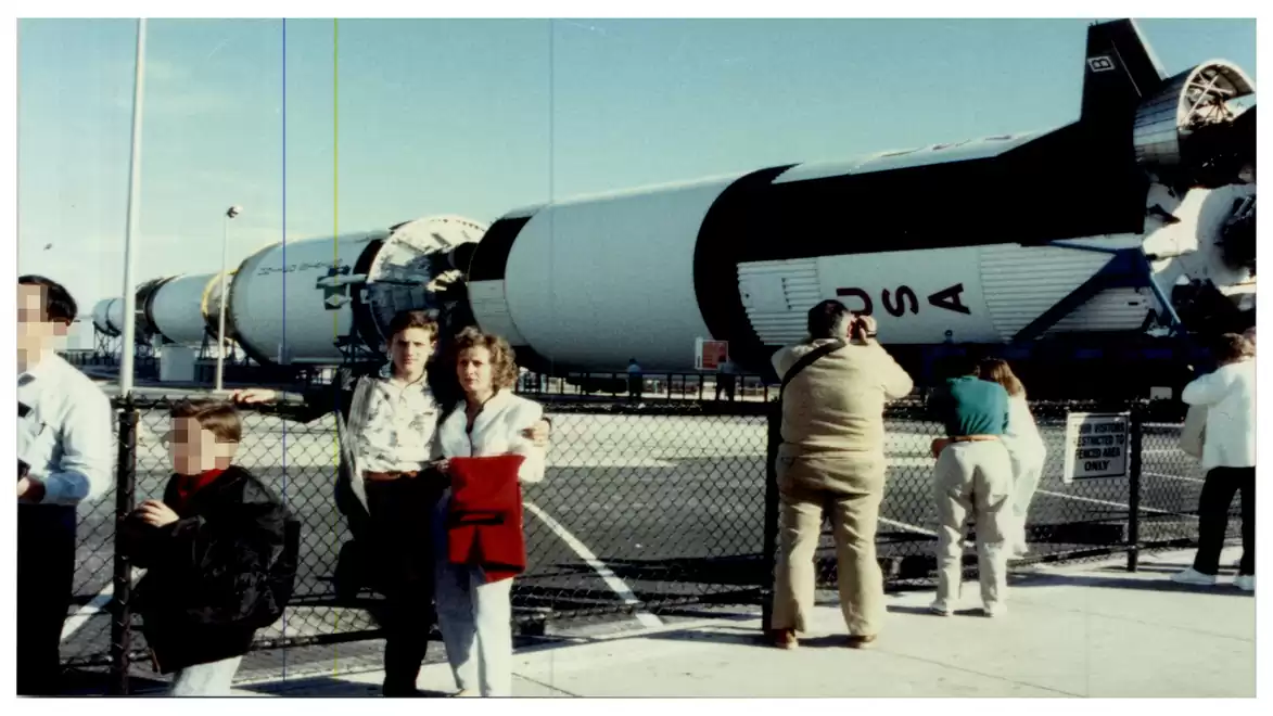People standing in front of a large rocket displayed at an exhibition area.