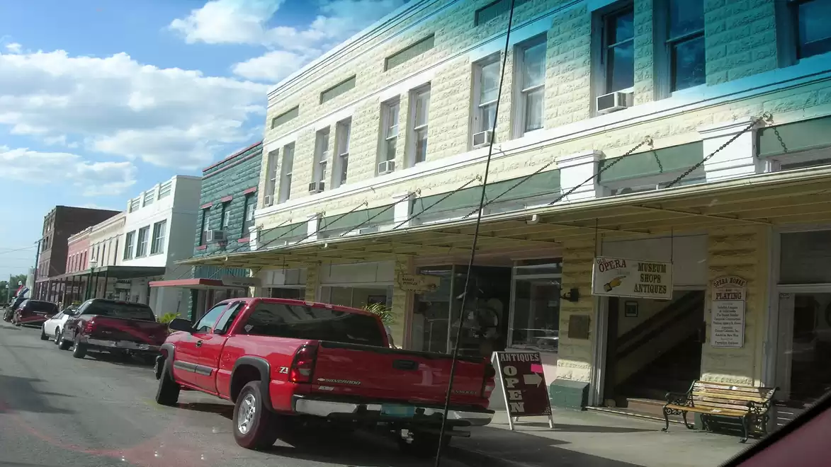 Street scene with parked cars and historic buildings under a clear sky.
