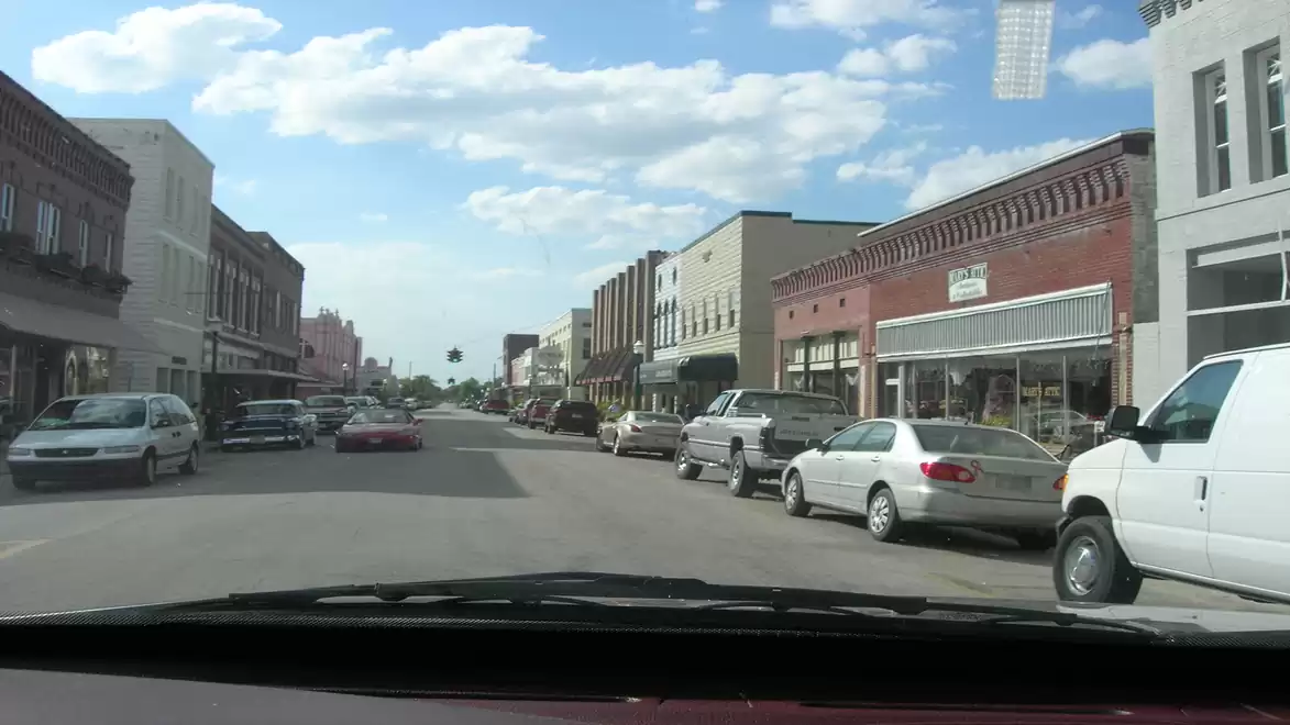 Urban street scene with parked cars and old buildings during daylight.
