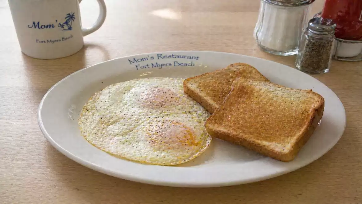 Breakfast with fried eggs and toast on a white plate in a restaurant.
