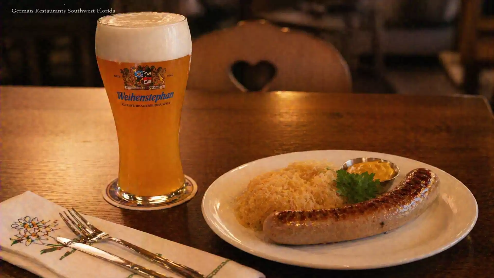 A mug of freshly poured beer and a plate with sausage and sauerkraut on a wooden table in a German restaurant.