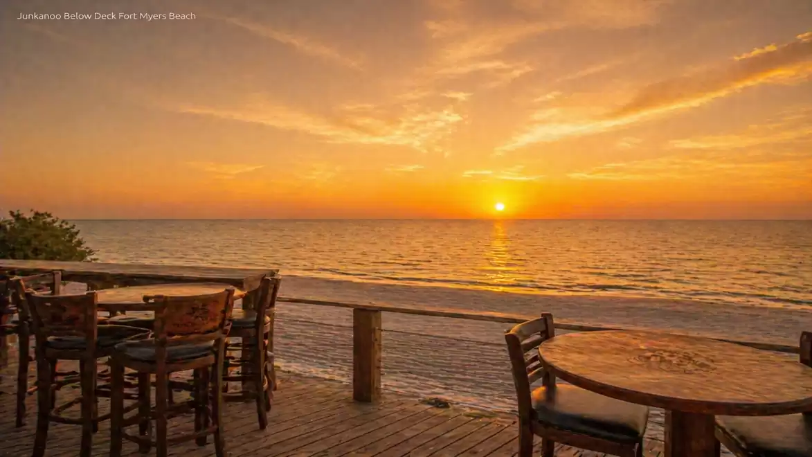 Sunset on the beach with a wooden deck and tables, scenic ocean view.