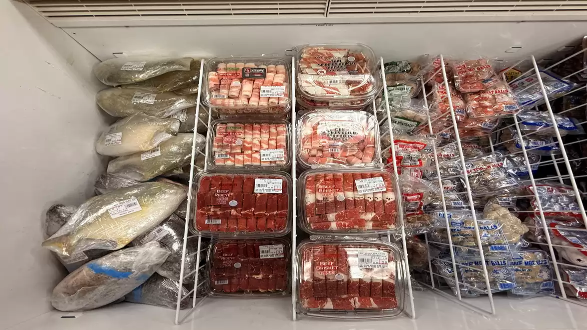 Freezer containing various packaged foods, including fish and seafood in plastic packaging.