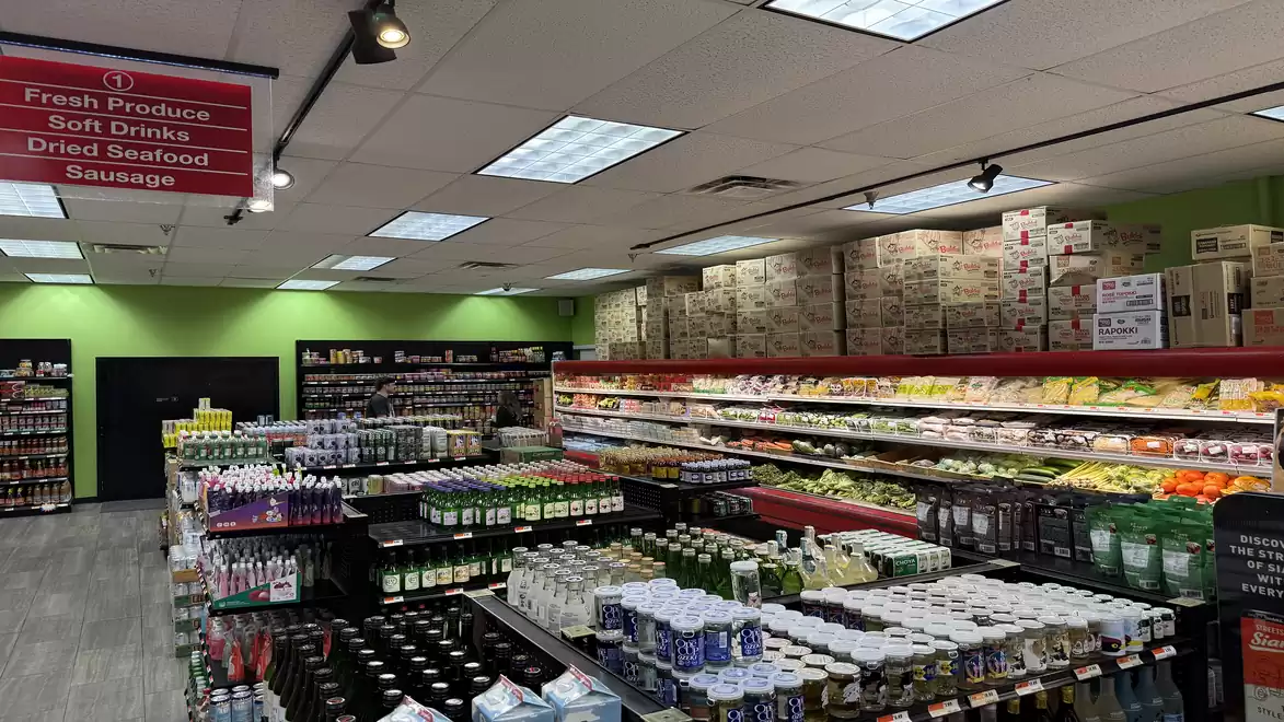 Interior view of a modern grocery store with well-stocked shelves of fresh produce, beverages, and other goods.