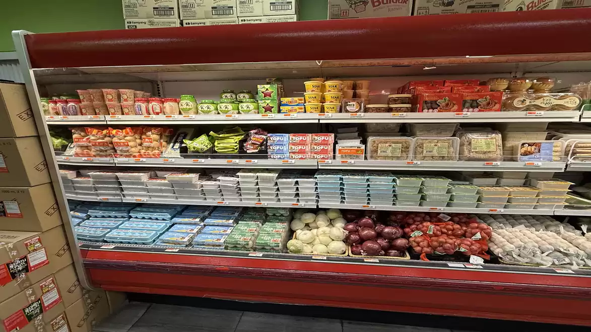 Supermarket shelf filled with a variety of fresh products including vegetables, fruits, and packaged foods.