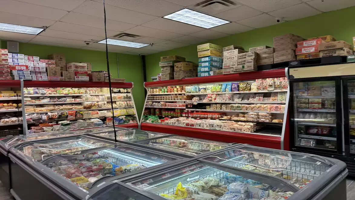 A well-stocked store featuring a selection of frozen goods and shelves filled with various food items on the left side.