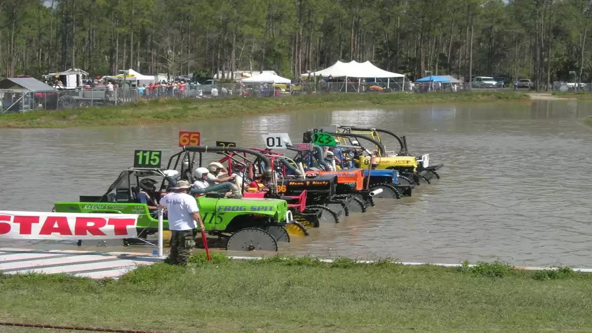 UIMF vehicle race starting in the water with several colorful off-road vehicles at the starting line.