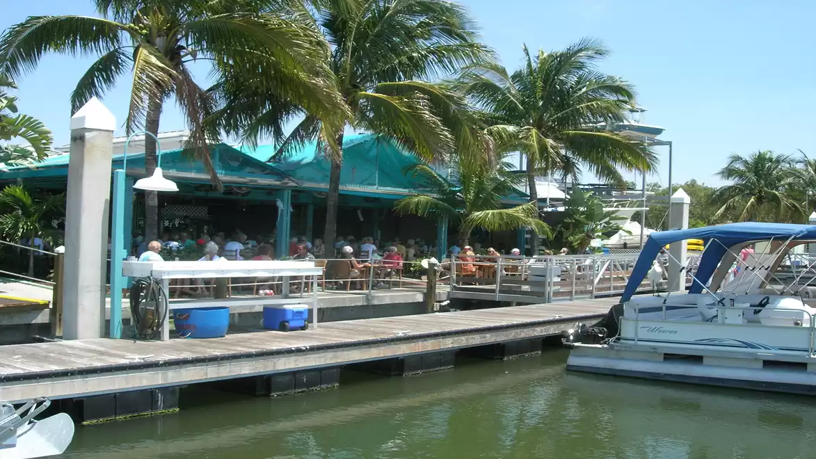 A picturesque harbor with palm trees, a dock, and a restaurant.