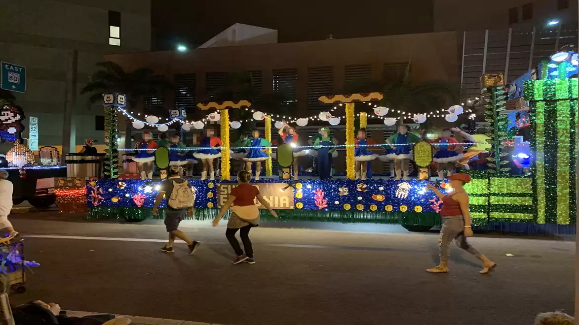 Image of a colorful carnival parade at night with a decorated float and participants in costumes.