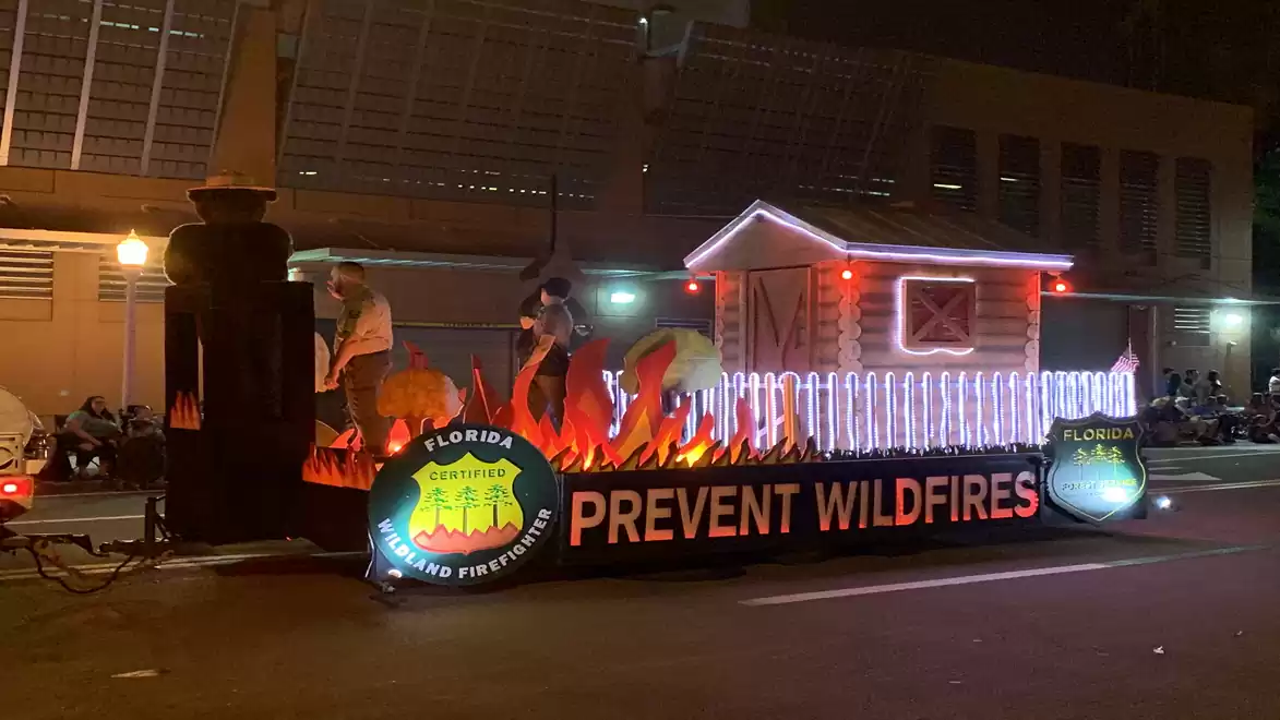 Illuminated float with flames and a cabin, promoting wildfire prevention.