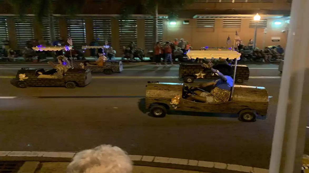 Night parade with decorated miniature cars and spectators.