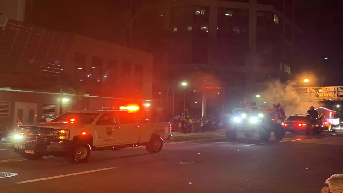 Night scene of an intersection with emergency vehicles and flashing lights.