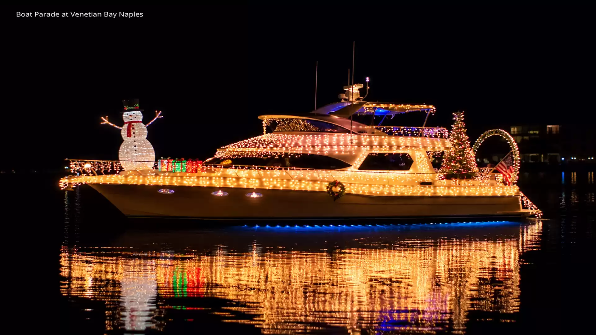 A boat decorated with festive lights and a snowman floats at night during a boat parade at Venetian Bay in Naples.