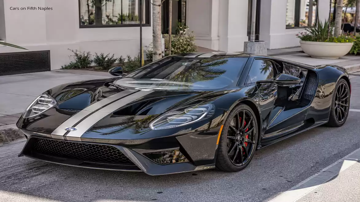 Black sports car with white stripes parked on urban street.
