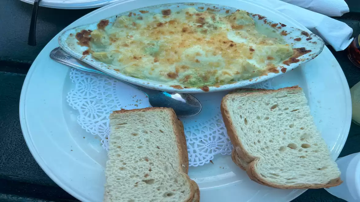 A plate with a baked dish and two slices of white bread on a white plate.