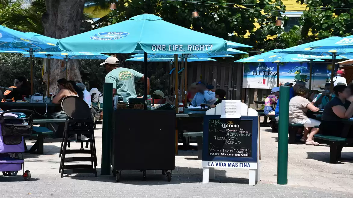 Street café with green umbrellas, people dining outside.