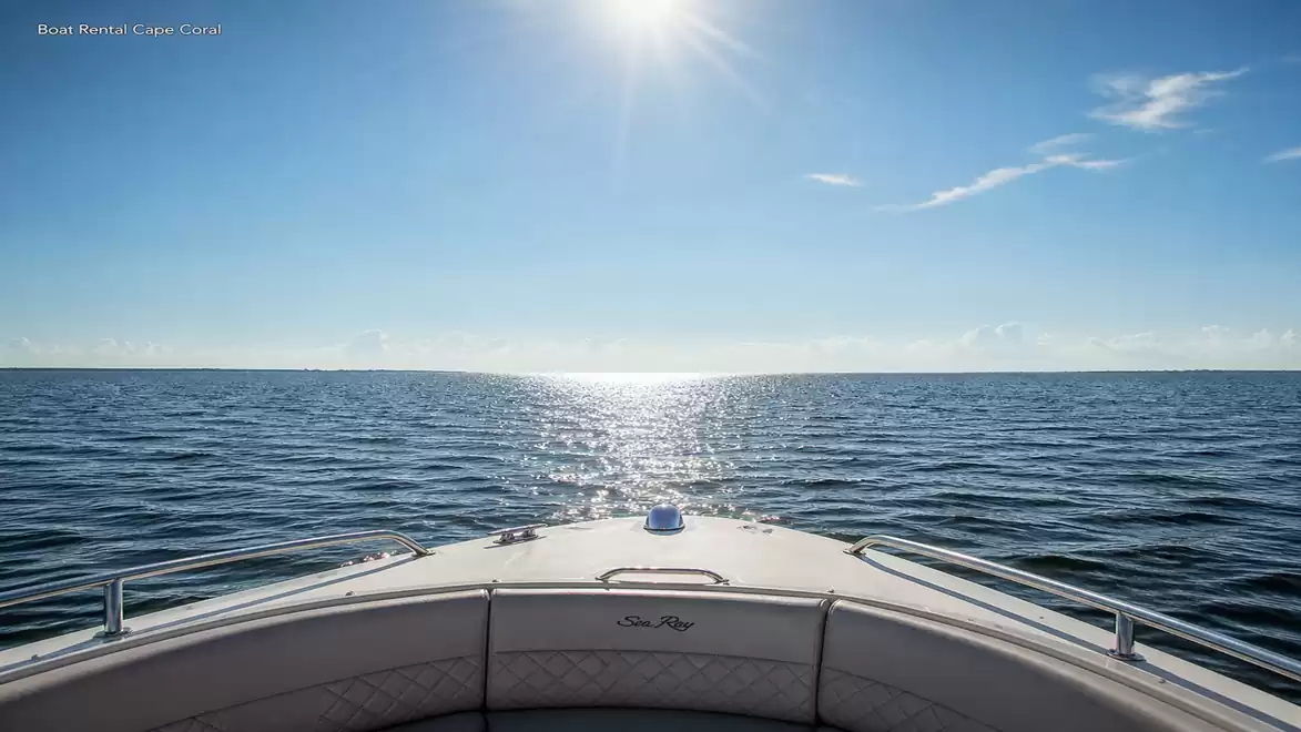 A boat on a calm sea under a clear blue sky, with sunshine and few clouds.